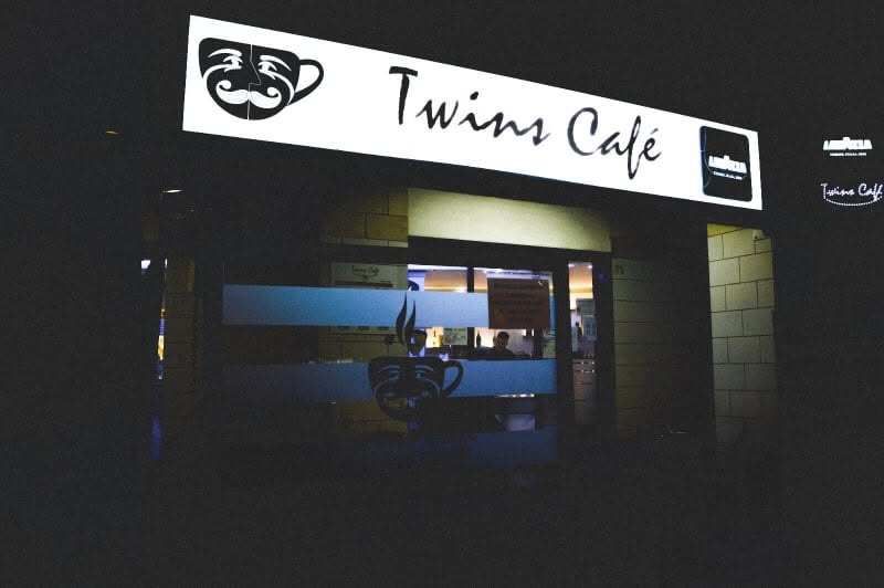 L’insegna e l’ingresso illuminati di Twins Café di sera